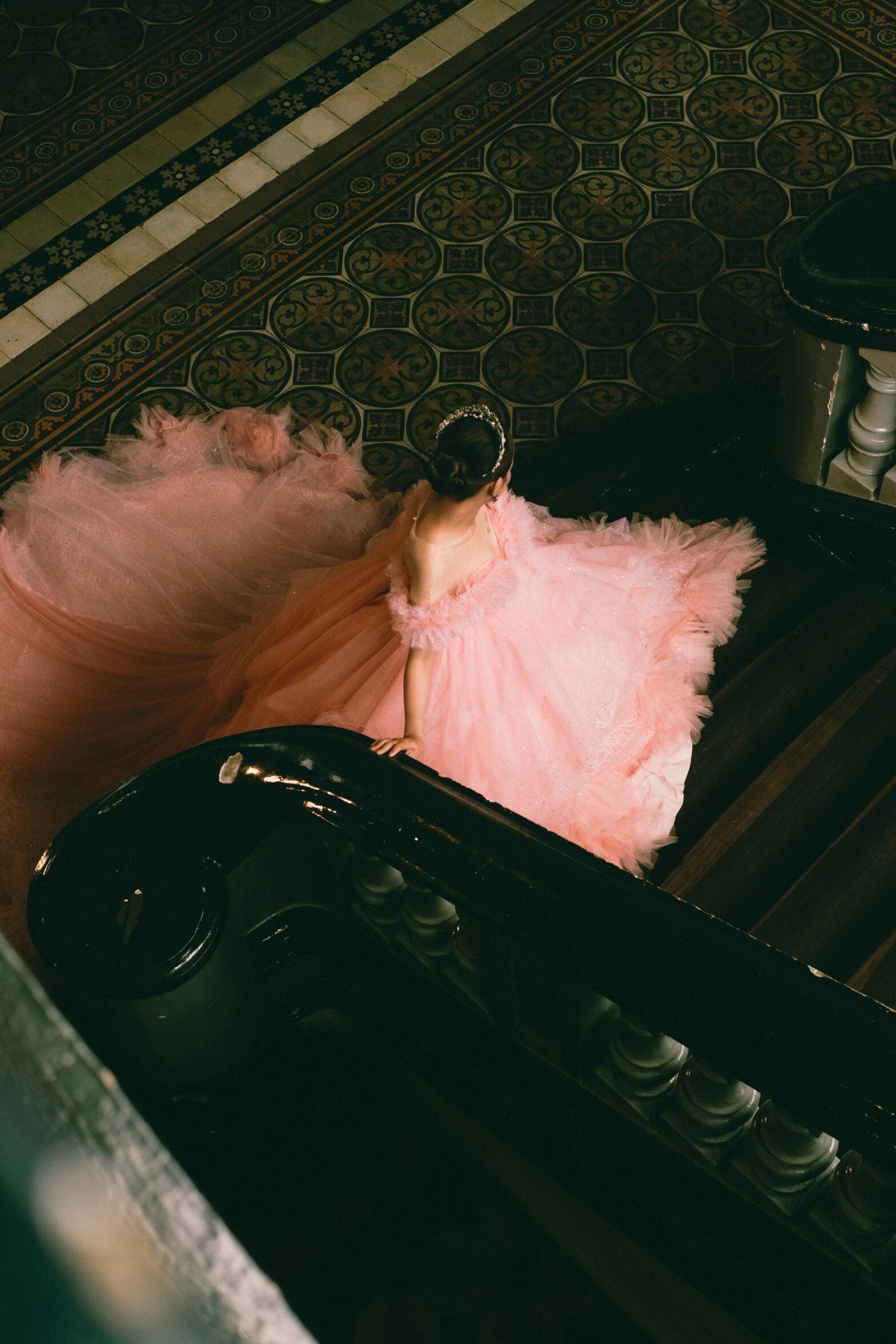 woman in a large and beautiful pink dress at the bottom of a staircase.