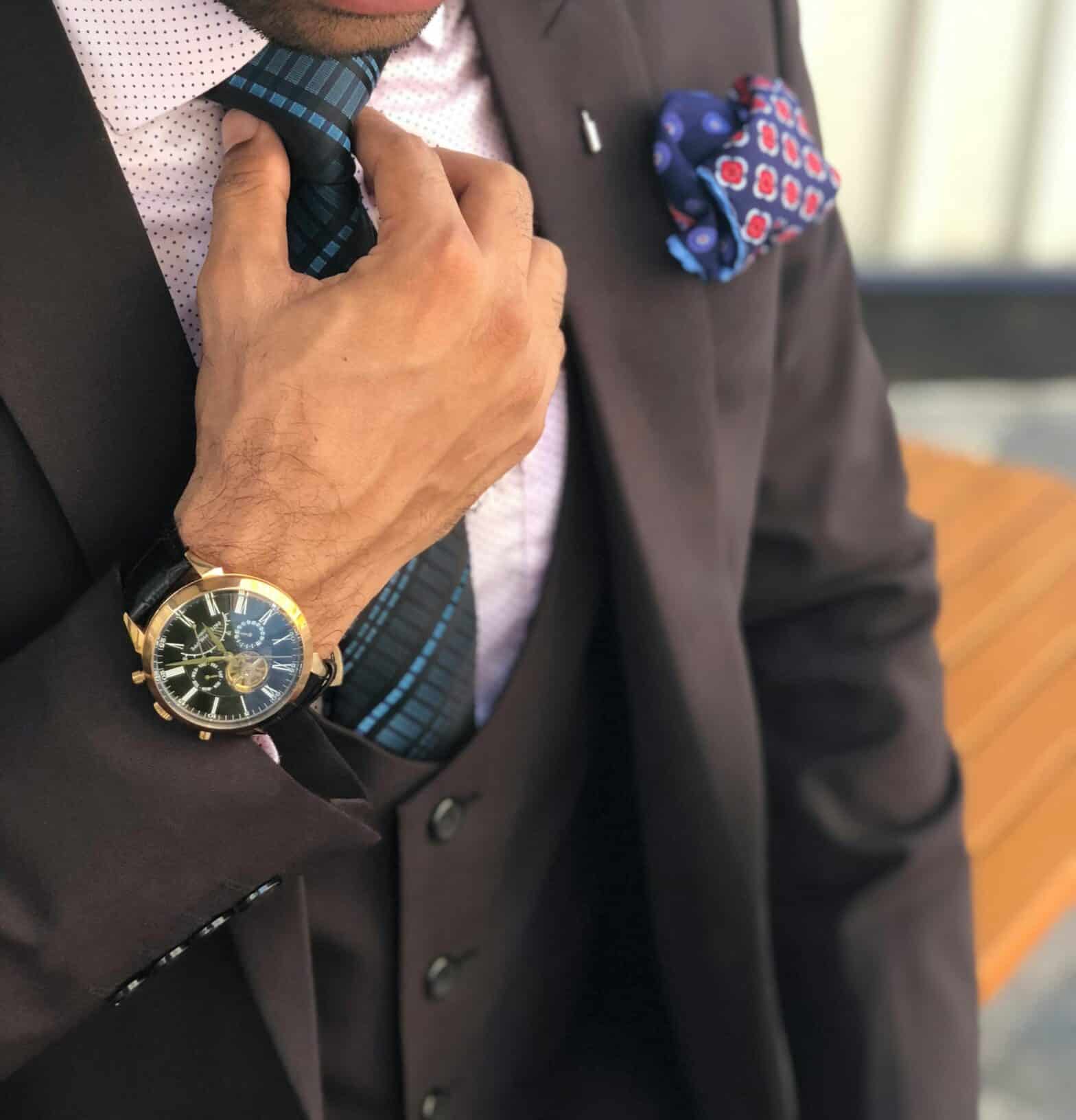 close up of a man wearing a nice suit and tie with a gold watch on his wrist